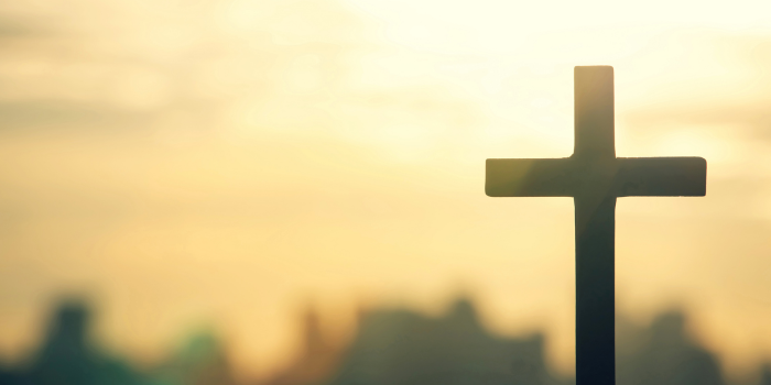 cross in foreground with sun behind